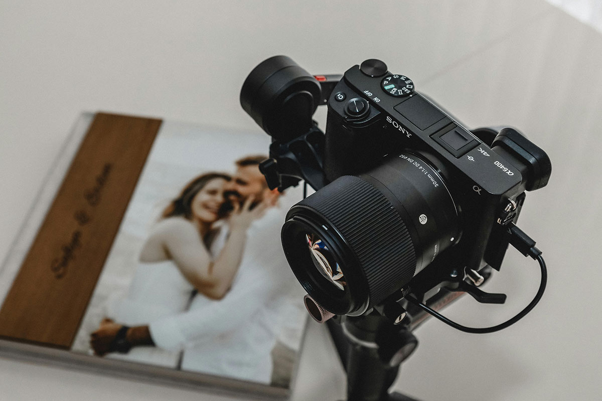 pexels-recepcelikphoto-23384885 A digital camera on a tripod, above a wedding album on a white surface.