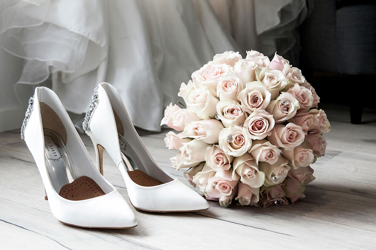 pexels-solliefoto-313707 A bouquet next to white wedding heels, in front of a wedding dress.